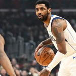 Kyrie Irving, wearing a Dallas Mavericks jersey, celebrates on the court with intensity after a dominant performance, emphasizing the importance of defending their home arena.